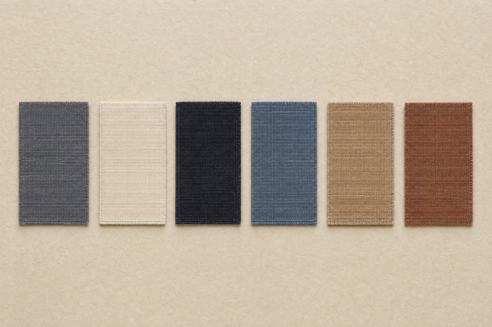 Six fabric swatches laid in a row: slate grey, oat white, deep ink, ash blue, camel and brick brown.