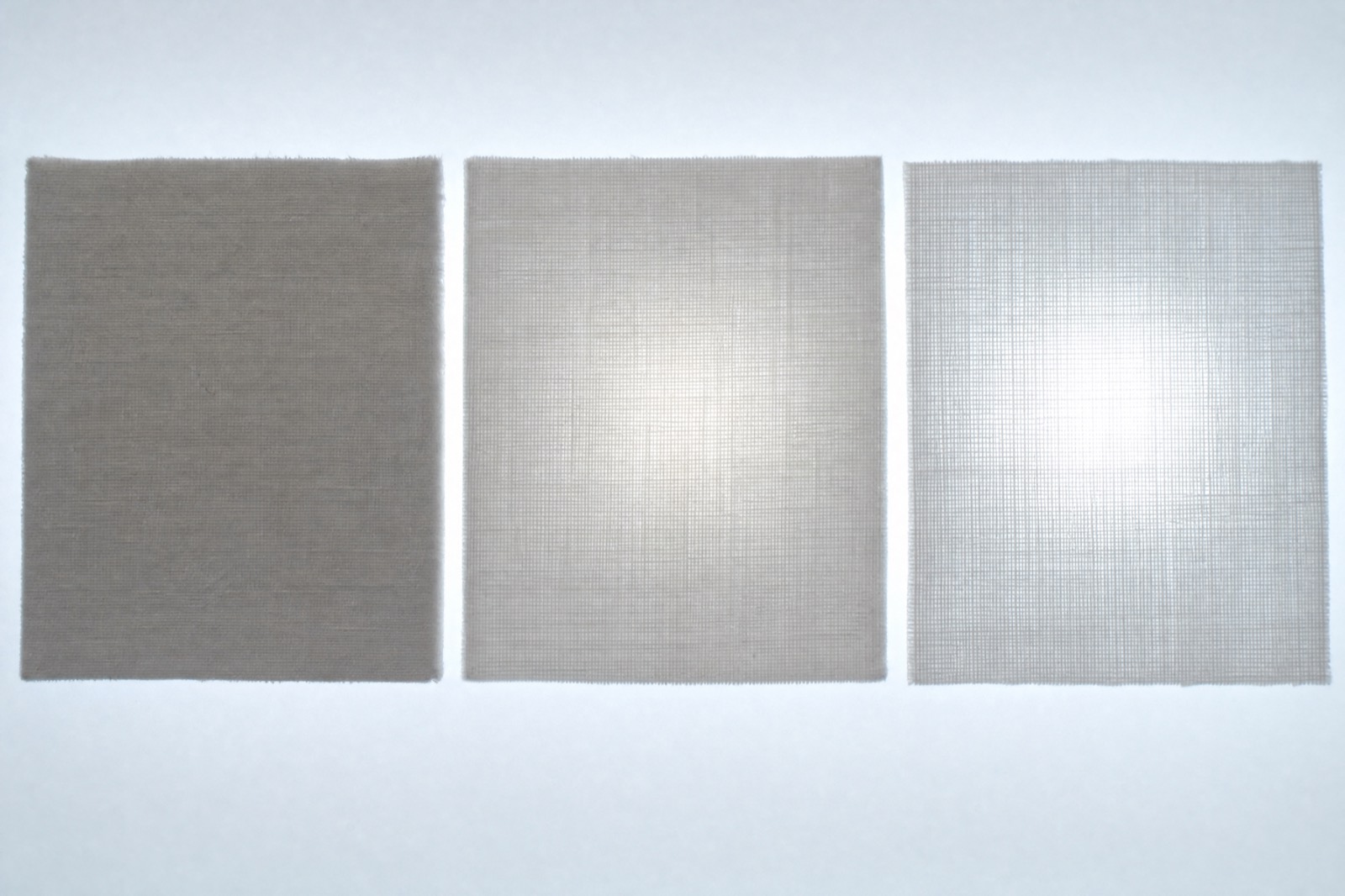 Three panels of pale cloth against a lightbox: the left blocks the light, the middle glows softly, the right is clearly translucent.
